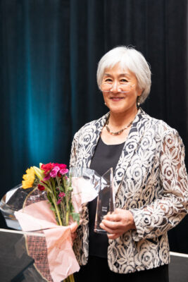 Unmi Song posing for a photo with her Local Champion Award.
