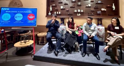 AAPIP “Building AAPI Power” panel with four speakers seated on a low stage in a decorative Asian cultural space. A presentation screen identifies the panelists: Jade Nguyen (Việt Place Collective), Jimmy Le (Hamkae Center), and Luis Angel Aguilar (We Are CASA).